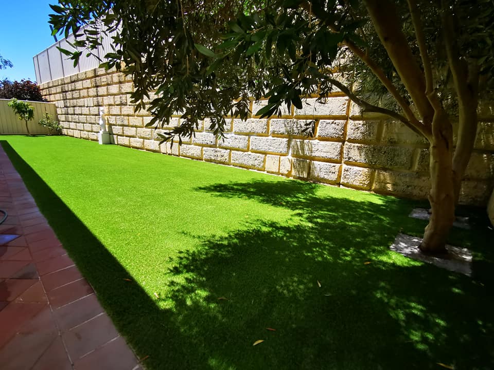 Limestone block retaining wall with paving and artificial grass, built by Artificial Outdoor Solutions